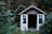 A cozy wooden shed surrounded by greenery with a saxophone resting on a workbench inside.