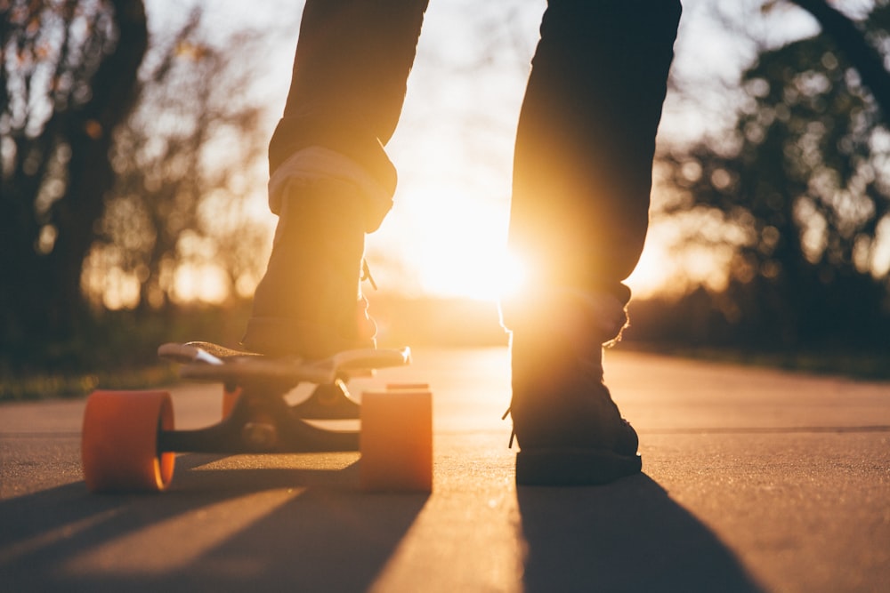 man putting left foot on longboard against sunglight