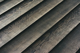 Wooden planks laid out in a parallel arrangement, displaying a textured surface with natural grain patterns.
