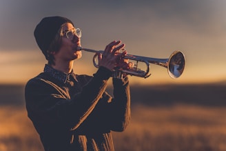 Eric Miglin playing trumpet with a warm smile on stage at a cozy jazz venue.