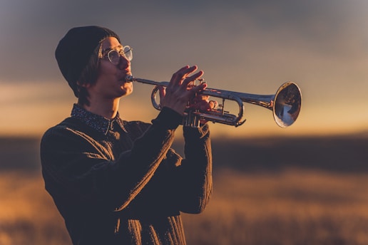 Eric Miglin playing trumpet with a warm smile on stage at a cozy jazz venue.