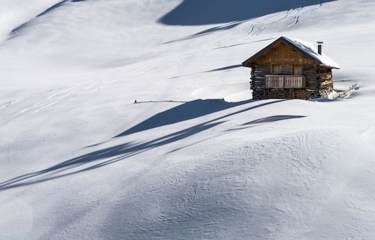 brown wooden house covered of snow in Pozza di Fassa Italy