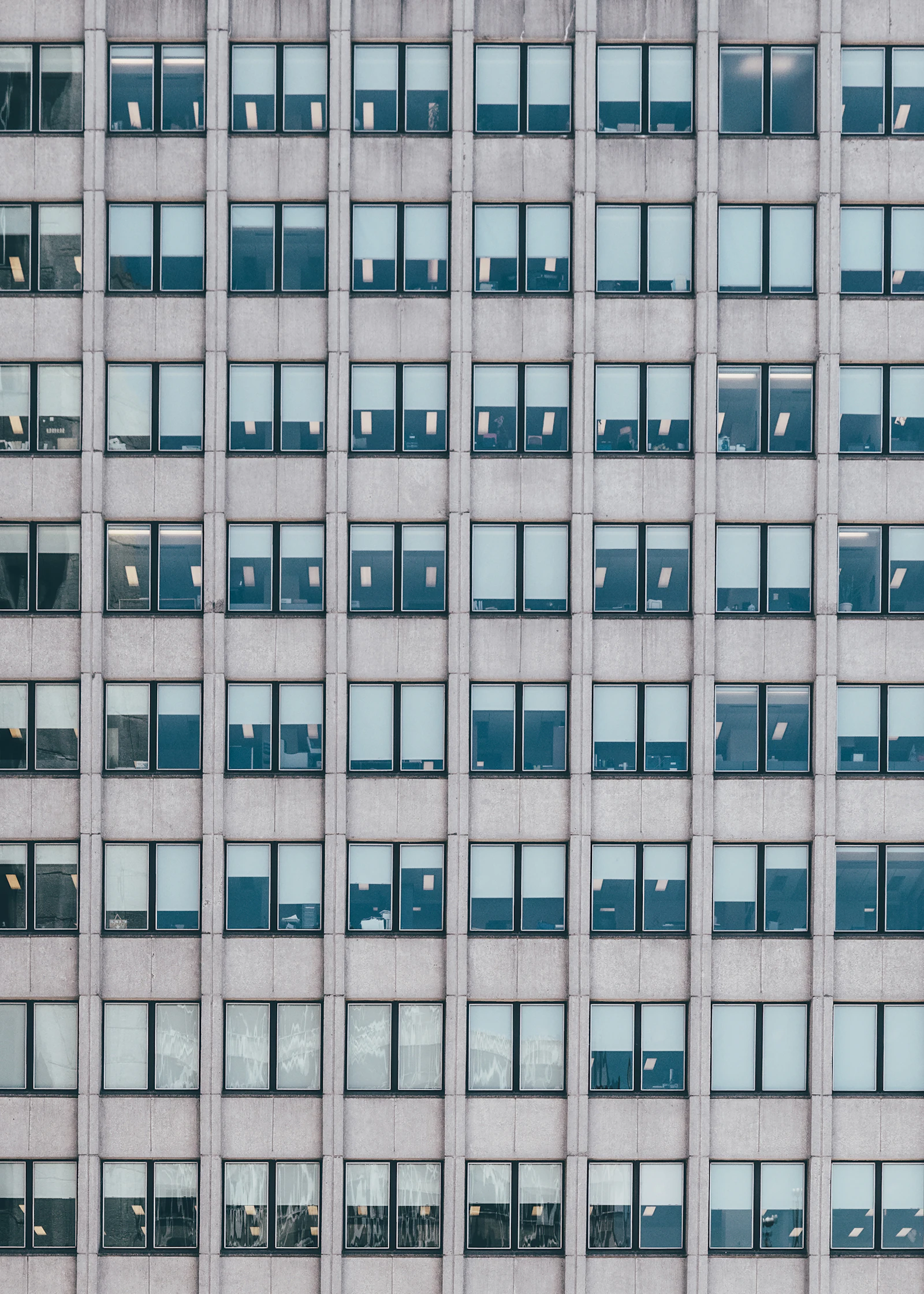 A tall office facade of repeating windows in flat grey light