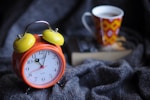 orange and yellow analog alarm clock at 11:03