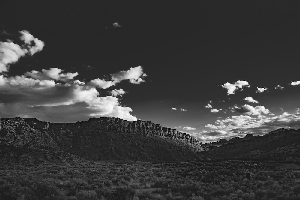 grayscale photo of mountain under cloudy sky