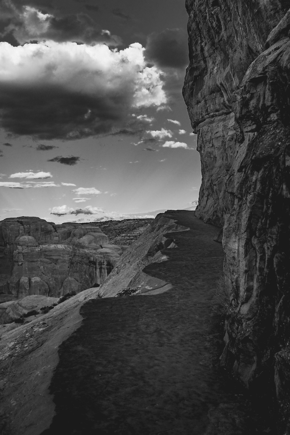 grayscale photo of rocky mountain under cloudy sky