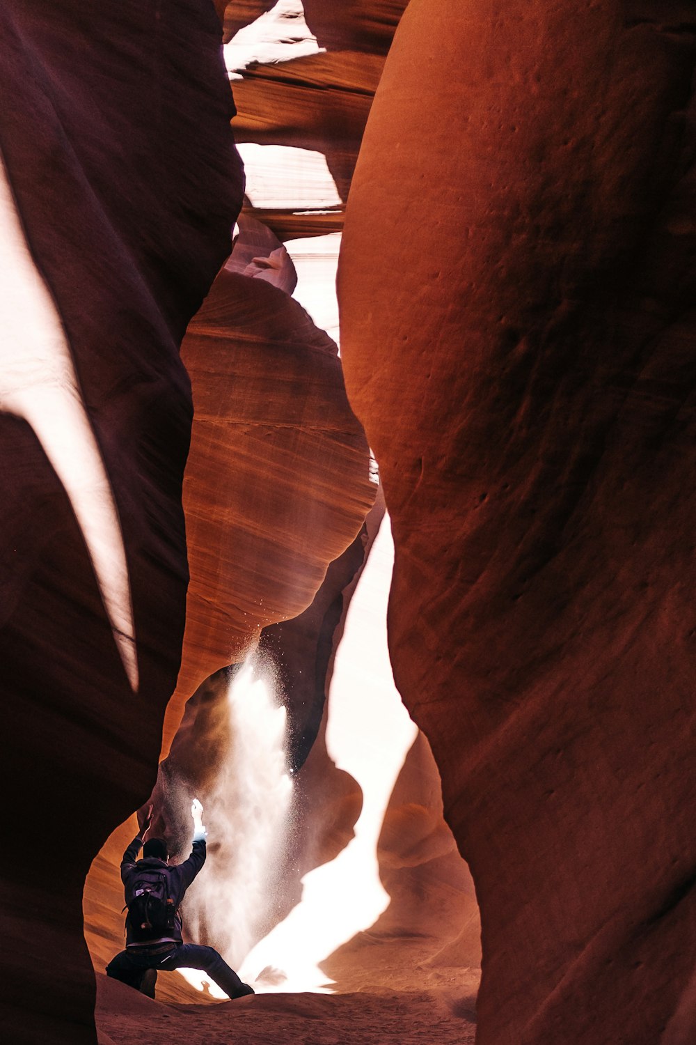 person in black pants standing on brown rock formation during daytime