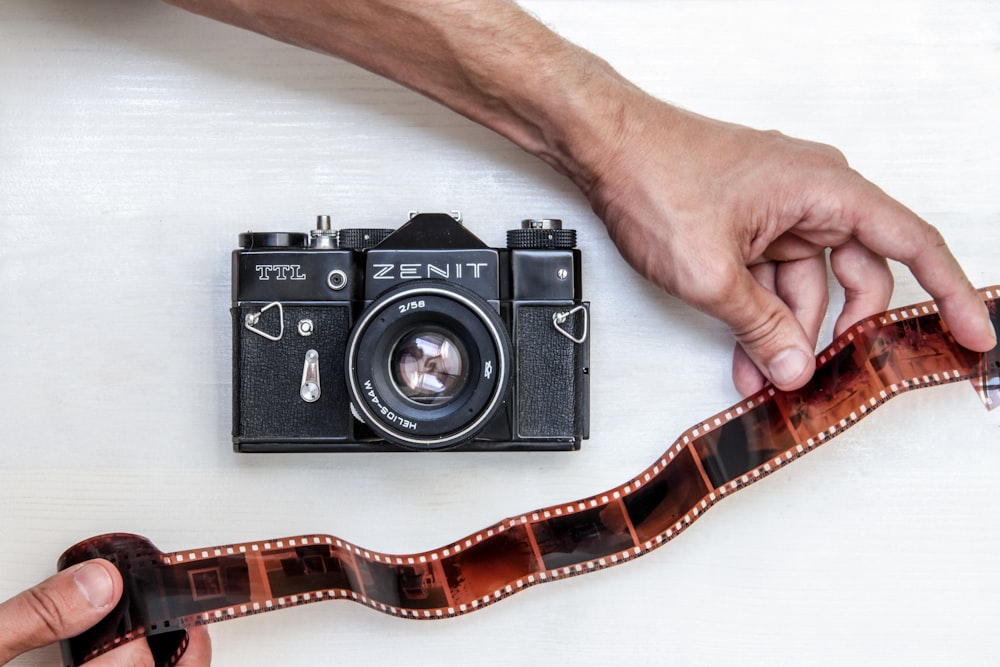 flat lay photography of person showing photo film beside Zenit DSLR camera