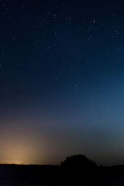 A serene night sky with softly glowing stars above a peaceful horizon.