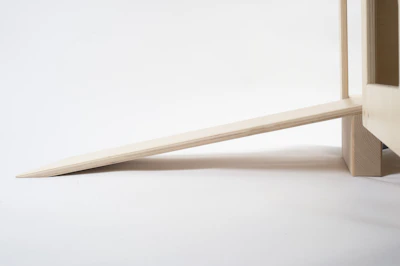 Close-up of a sleek, black heavy-duty rubber door stopper holding a wooden door in place on a light hardwood floor.