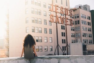 woman in gray top sitting on a building's edge
