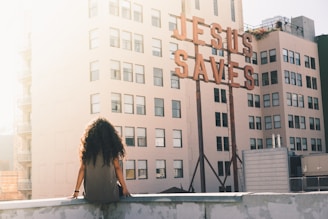 woman in gray top sitting on a building's edge