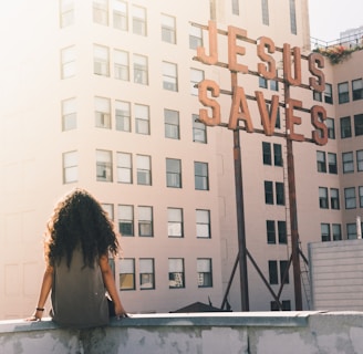 woman in gray top sitting on a building's edge