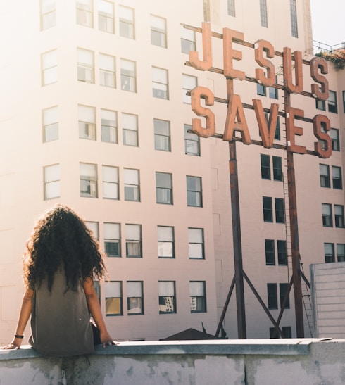 woman in gray top sitting on a building's edge