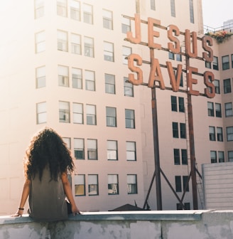 woman in gray top sitting on a building's edge