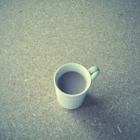 A serene morning scene featuring a handcrafted ceramic mug filled with tea on a wooden table.