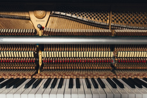 Hands regulating piano action parts inside an upright piano.