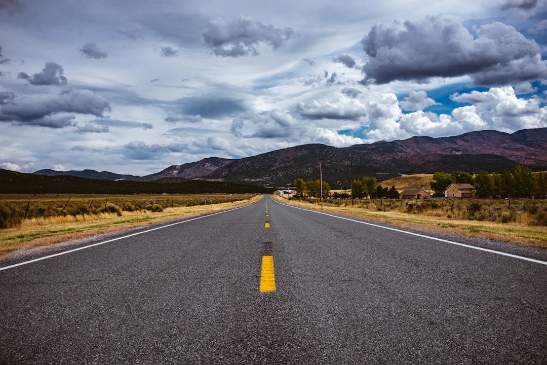 gray concrete road under white clouds and blue sky during daytime