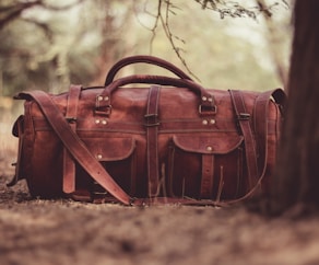 selective focus photography brown leather 2-way handbag near tree