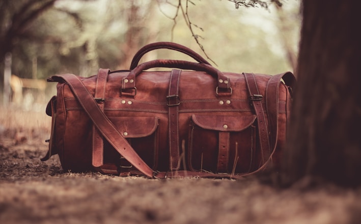 selective focus photography brown leather 2-way handbag near tree