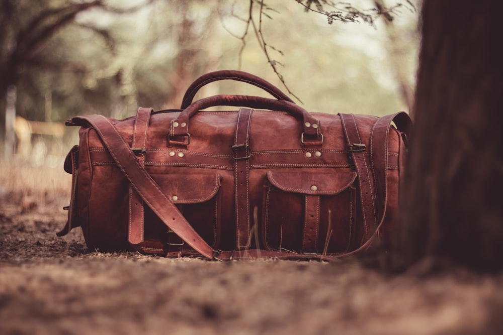 selective focus photography brown leather 2-way handbag near tree