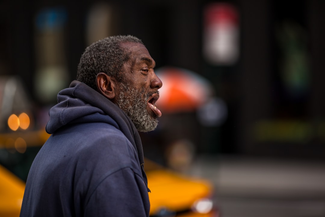 man in black hoodie standing on street during daytime