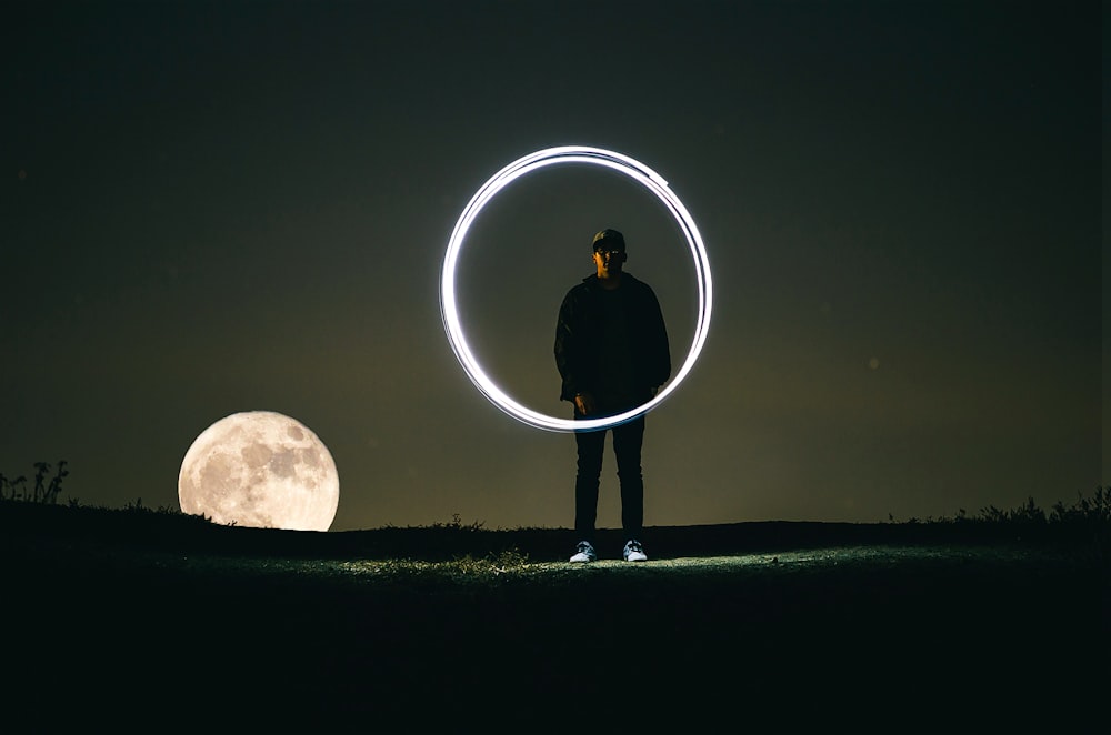 Mann steht bei Vollmond auf dem Hügel