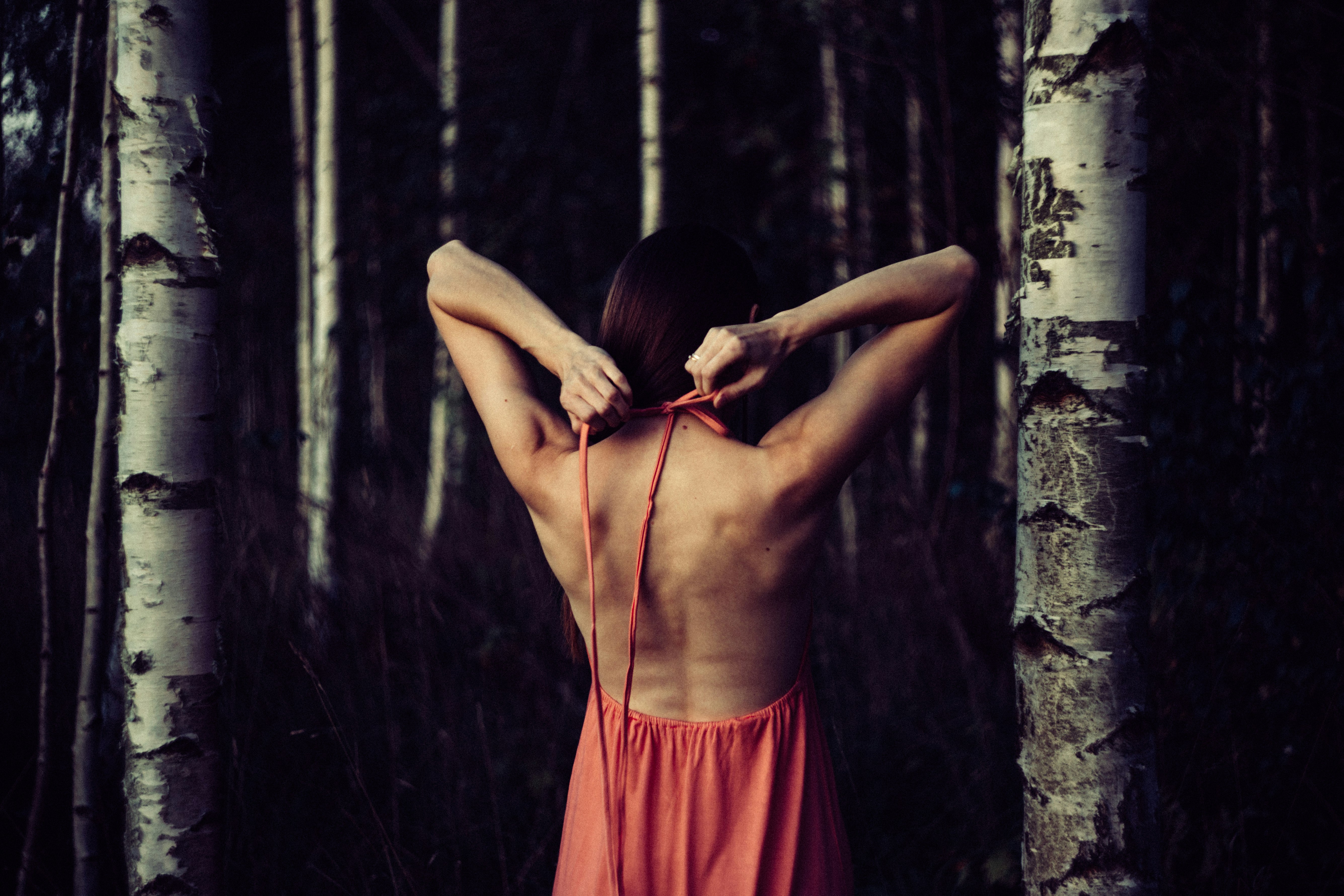 A girl stretching with her arms behind her back inside a forest.