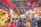 A bustling indoor market filled with people shopping and browsing various stalls that sell clothing, souvenirs, and food. The market is vibrant with colorful signage, decorations, and displays of merchandise. The scene is lively and crowded, conveying a sense of a busy shopping environment.
