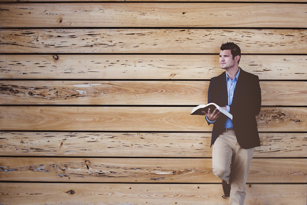 man leaning on wooden wall