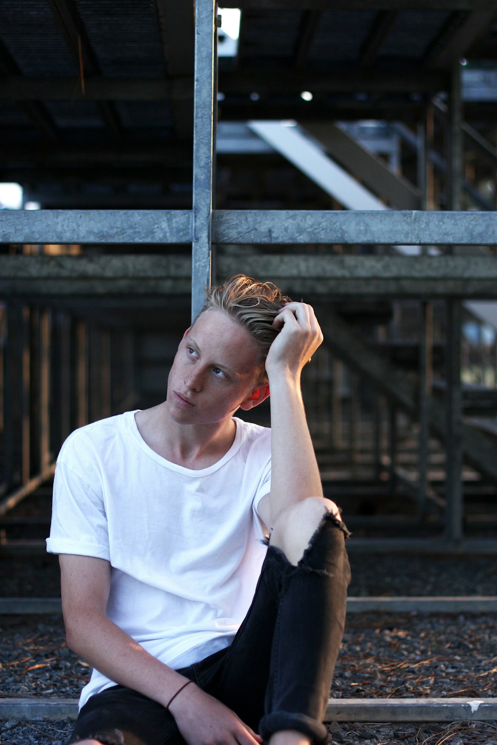 man sitting on floor wearing white crew-neck T-shirt