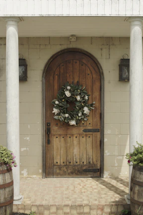Outdoor patio decorated with a lush artificial flower wreath hanging on a wooden door.
