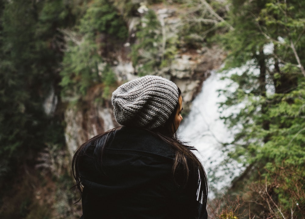 woman in black coat standing near mountain