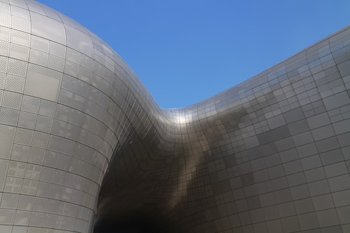 A sleek, modern industrial shade structure under a clear blue sky.