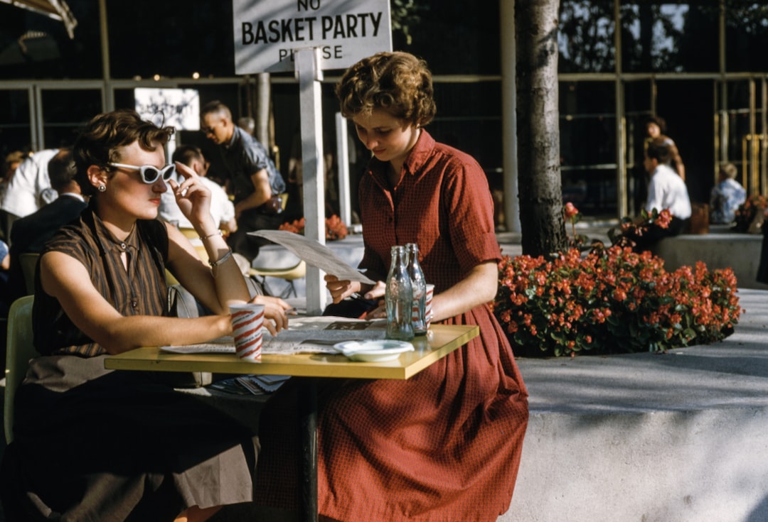 woman sitting in front of table with two empty glass bottles, vintage cafe scene