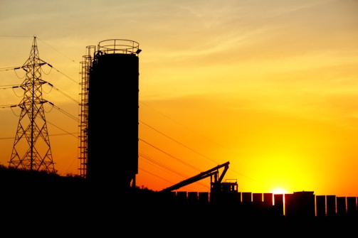 Curved corner image of a high-voltage transformer station at sunset.