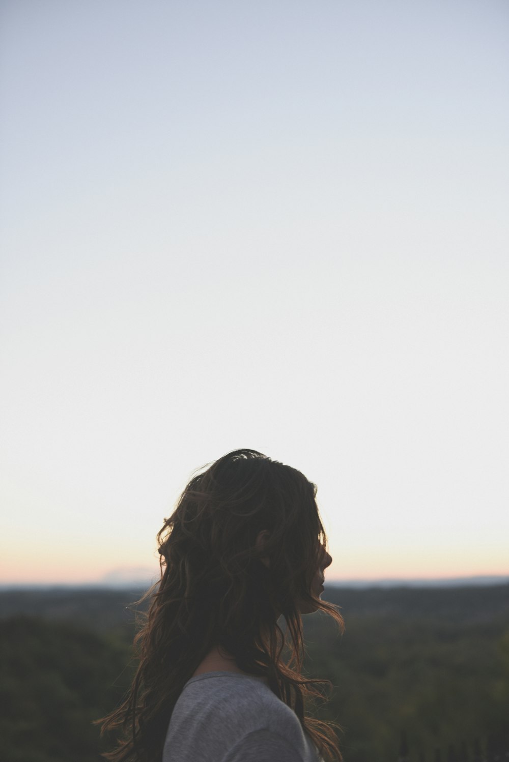 brunette hair woman wearing gray top looking side way