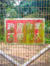 A vintage metal garden sign hanging on a wooden fence surrounded by climbing vines.