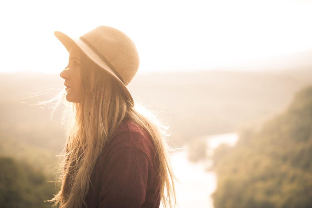 Hopeful woman looking to the side in a hat backlit by the sun