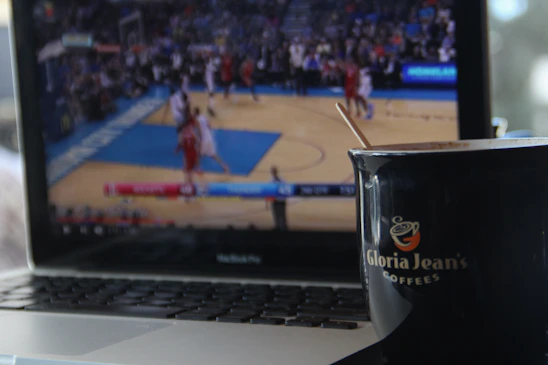 A focused bettor analyzing sports statistics on a laptop with a cup of coffee nearby.