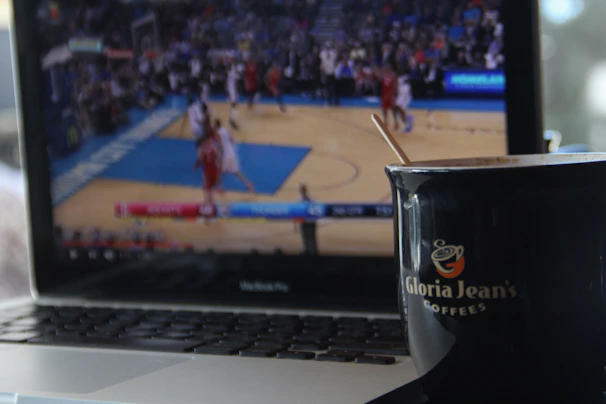 A focused bettor analyzing sports stats on a laptop with a cup of coffee nearby.
