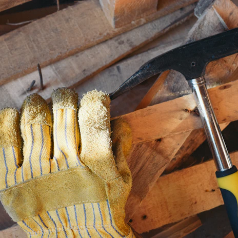 A stack of durable work gloves next to a measuring tape and safety helmet.