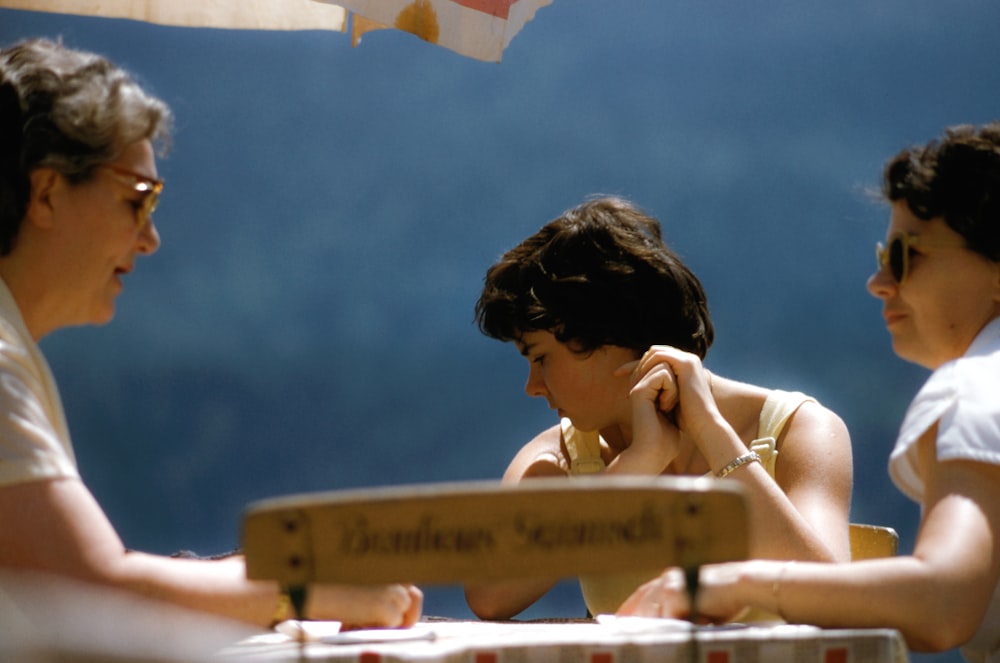 three person sitting beside table