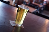 Freshly poured craft beer in clear glass with foamy head on wooden table.