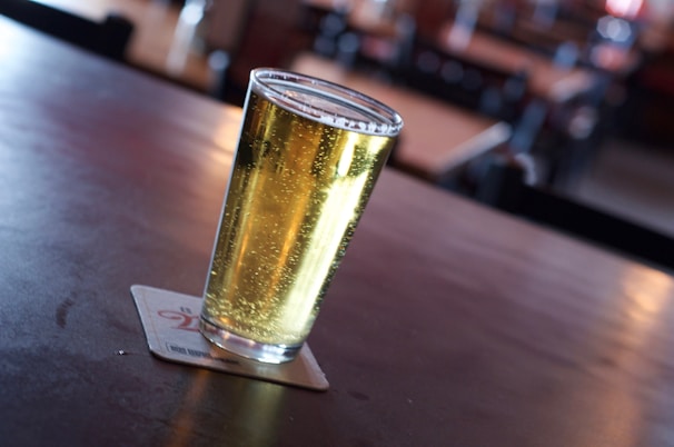 Close-up of a frosty Rocky Brewing beer glass with golden beer and foam on a wooden table at Praia Grande.