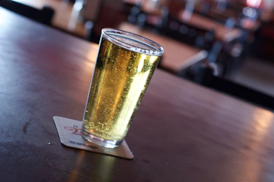 Close-up of a frosty craft beer glass with golden liquid and foam on a rustic wooden table