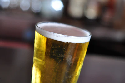 Close-up of golden beer foam with red and gold accents in the background.