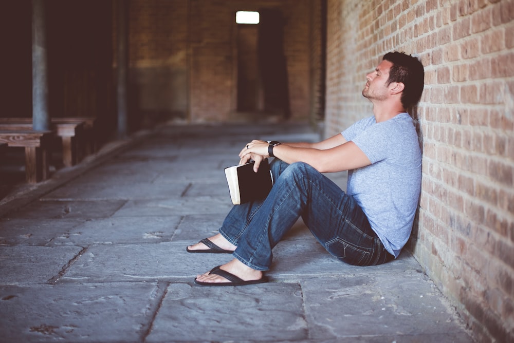 man sitting on pathway holding book at nighttime