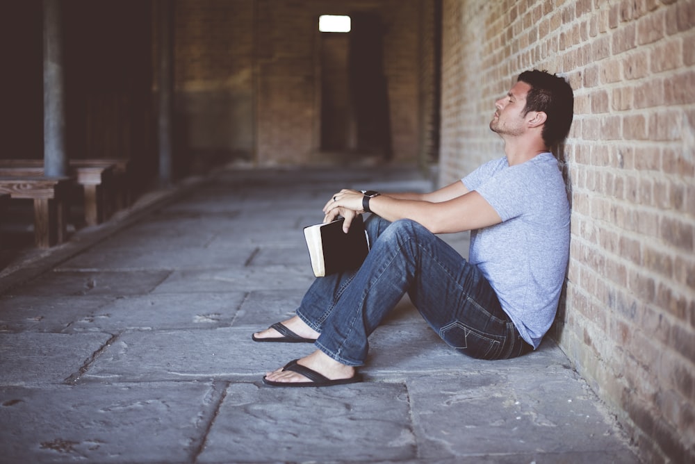 man sitting on pathway holding book at nighttime