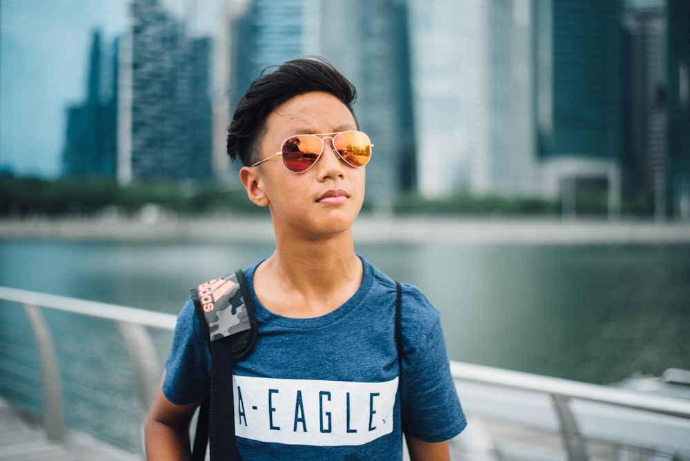 boy wearing yellow lens Aviator sunglasses near gray rail at daytime